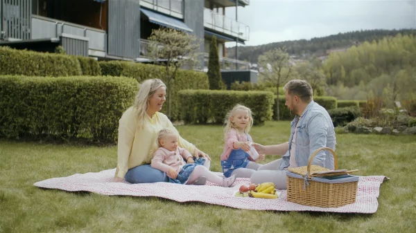 mor, far og barn som har piknik i hagen utenfor boligen