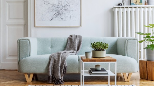 Moderne skandinavisk interiør med lyseblå sofa, teppe, og bilde på veggen.